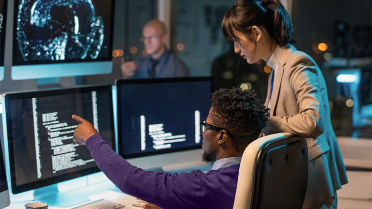 Funcionários de empresa de tecnologia olhando para código em computador e falando sobre inteligência artificial