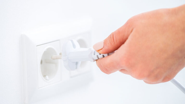 Mão de uma mulher tirando um equipamento da tomada