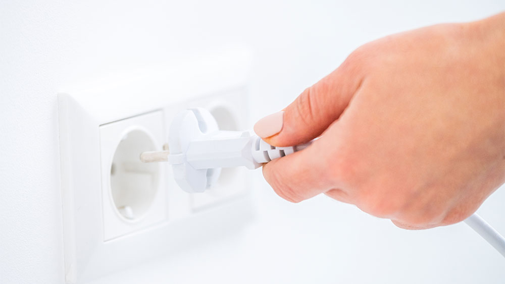 Mão de uma mulher tirando um equipamento da tomada