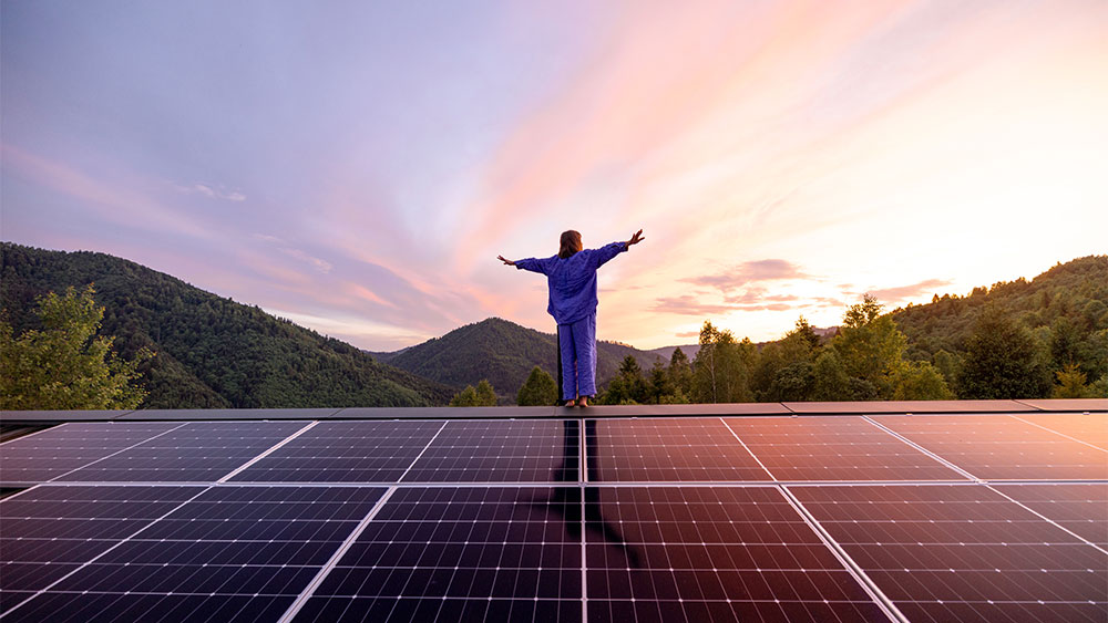 Mulher em cima do telhado de uma casa com painéis solares