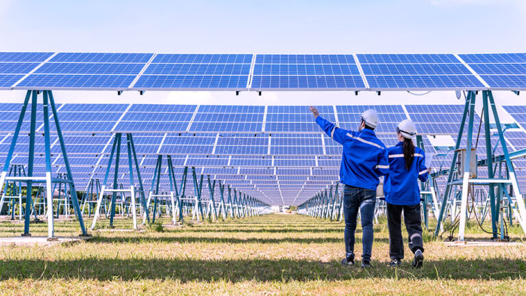 Profissionais analisam painéis solares em uma usina fotovoltaica, representando inovações tecnológicas no setor de energia verde.